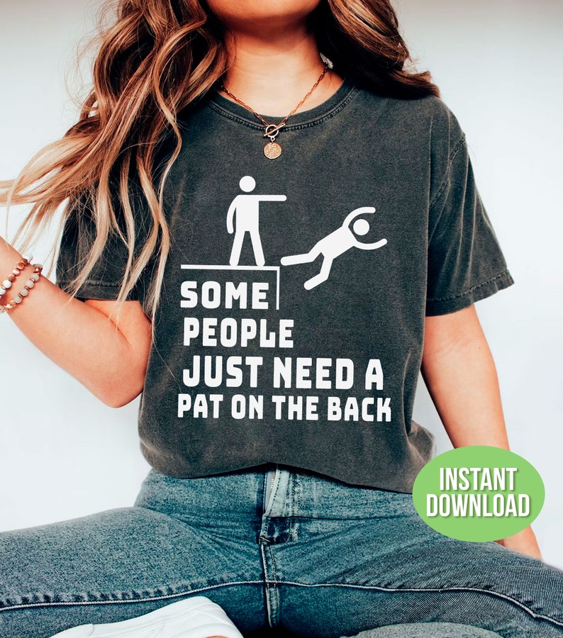 Pu&ograve; includere: T-shirt grigio scuro con la scritta "SOME PEOPLE JUST NEED A PAT ON THE BACK" e una grafica di una persona che ne spinge un'altra gi&ugrave; da un bordo. Un cerchio verde con "INSTANT DOWNLOAD" &egrave; in basso a destra.