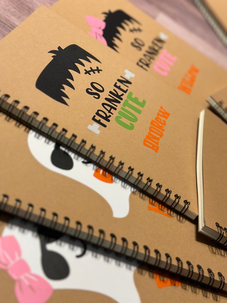 Puede incluir: Cuadernos de papel kraft con encuadernaci&oacute;n de alambre negro. Las cubiertas presentan dise&ntilde;os tem&aacute;ticos de Halloween, incluyendo un monstruo de Frankenstein con el texto "So Franken Cute" y un fantasma con un lazo rosa. El nombre "Andrew" tambi&eacute;n est&aacute; impreso.