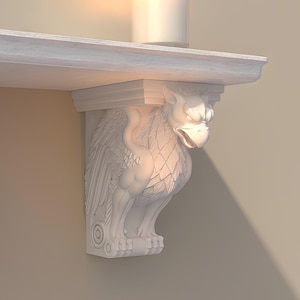 May include: A white wall-mounted shelf supported by two sculpted griffin brackets. The shelf holds a green plant in a terracotta pot and a white pillar candle in a clear glass holder. The structure features detailed carvings of winged creatures.