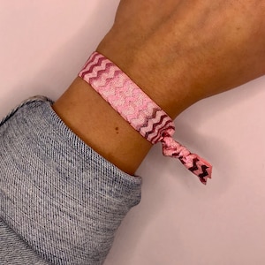 Op de afbeelding: Een roze en wit gepatroneerd elastiekje voor haar met een zigzagontwerp.