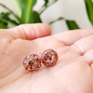 Peut inclure: Une paire de petites boucles d'oreilles rondes avec une base en résine transparente et des fleurs pressées roses et vertes à l'intérieur.