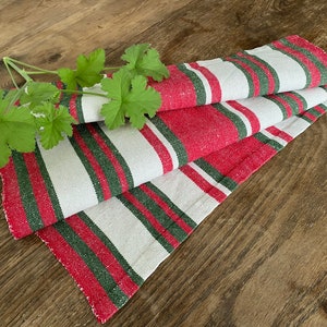 May include: A folded red, white and green striped kitchen towel on a wooden surface.