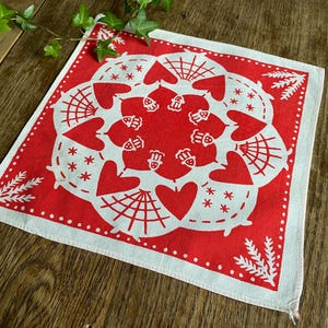 May include: Red bandana with a white design of hearts, stars, and a spiderweb pattern. The bandana has a white border with small red dots.