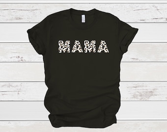 May include: Black t-shirt with the word "MAMA" in white letters with a black and white animal print pattern. The shirt is made of a soft material and has short sleeves.