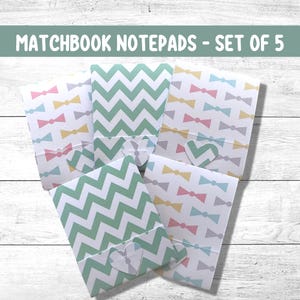 May include: Set of five matchbook notepads with a variety of designs. The notepads feature a chevron pattern, a bow tie pattern, and a heart-shaped cutout. The notepads are ideal for jotting down notes, reminders, or to-do lists.