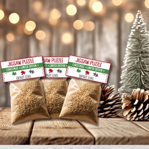May include: Three small bags filled with brown jigsaw puzzle pieces, each with a red and green Christmas-themed label that reads "Jigsaw Puzzle Christmas + Limited Edition + Expert Level".
