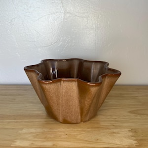 May include: A set of three ceramic mugs with a speckled, matte finish. The mugs are in shades of cream, light gray, and dark gray. Each mug has a simple, minimalist design and a rounded handle. The mugs are stacked on top of each other.