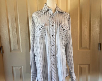 May include: A white long-sleeved button-down shirt with thin blue stripes. The shirt has a pointed collar, two chest pockets, and a button-up front.