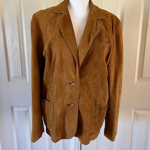 May include: A brown suede blazer with a notched collar, two button closure, and two flap pockets.