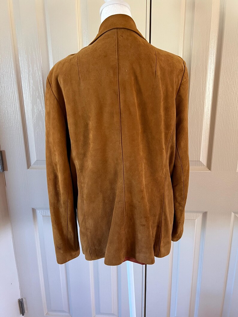 May include: A brown suede jacket with a collar and long sleeves.
