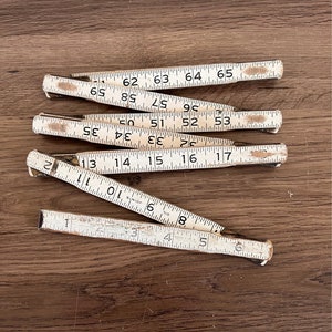 May include: A set of six vintage wooden folding rulers with white markings. The rulers are numbered from 1 to 65.