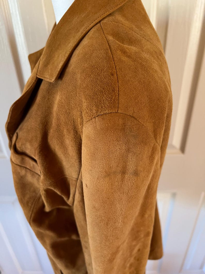May include: A brown suede jacket with a collar and long sleeves. The jacket is made of a soft, textured material.