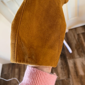 May include: Close-up of the brown suede fabric of a jacket sleeve.