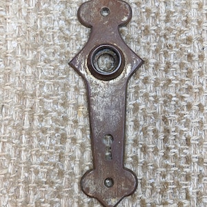 May include: A rusty metal door knob with a keyhole and a decorative design. The knob is a dark brown color and has a worn finish.