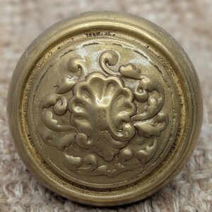 May include: A gold-toned metal door knob with a decorative floral design.