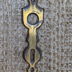 Peut inclure: Un cache-trou de serrure en laiton vintage avec un design orné. Le cache-trou a un trou de serrure au centre et un haut et un bas décoratifs.