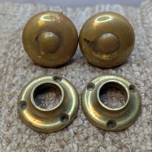 May include: Four antique brass door knobs. Two are round with a raised center and two are round with a hole in the center.