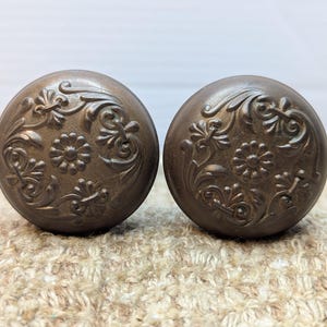 May include: Two antique brass door knobs with an ornate floral design.