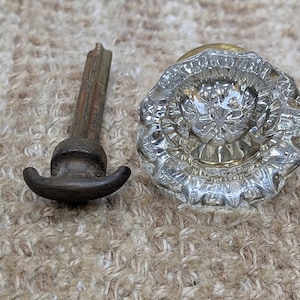 May include: A vintage glass doorknob with a brass base and a faceted design. The doorknob comes with a metal spindle.