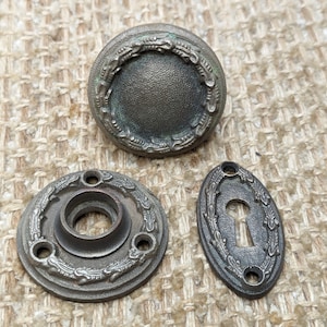 May include: A set of three antique door knobs with ornate floral designs. The knobs are made of metal and have a dark bronze finish.