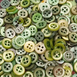 Pode incluir: Uma coleção de botões verdes e branco-sujos com quatro furos cada. Os botões variam em tons de verde, de claro a escuro, e são feitos de um material brilhante. Alguns botões têm um acabamento perolado.