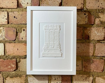 May include: A white framed print of a paper cut-out design of a building with intricate details. The design is in a white color and is framed in a white frame.