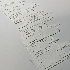 May include: A white paper cut-out of a building with a detailed facade, windows, and a tower. The text "e.g. Ennis..." is written at the bottom of the image.