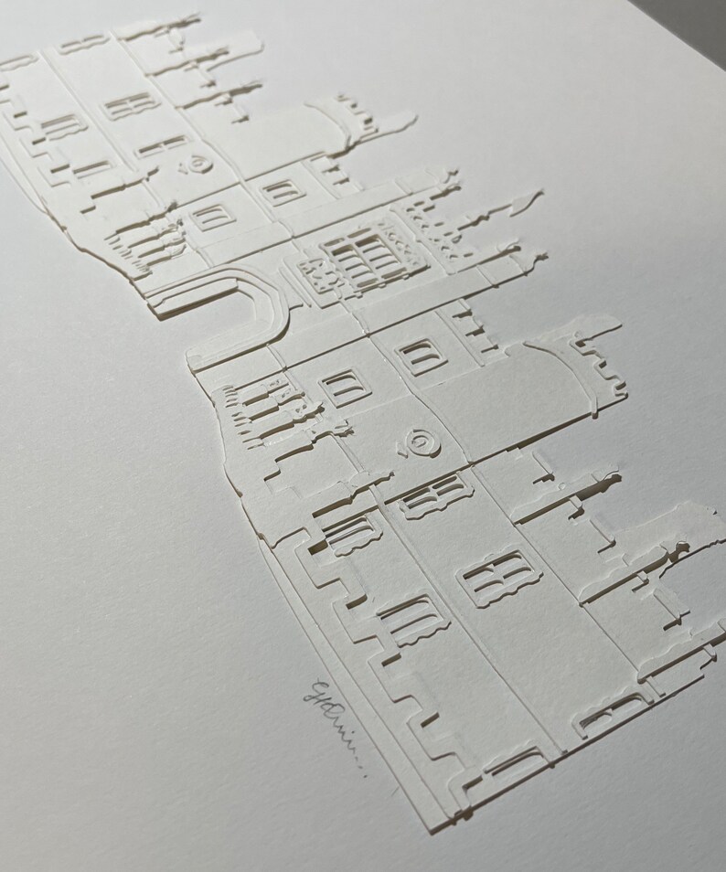May include: A white paper cut-out of a building with a detailed facade, windows, and a tower. The text "e.g. Ennis..." is written at the bottom of the image.