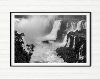 May include: A black and white photograph of Iguazu Falls, a series of waterfalls on the border of Argentina and Brazil. The falls are surrounded by lush greenery and mist.