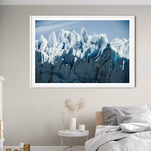 May include: A framed photograph of a glacier with a blue and white color scheme. The glacier is a large mass of ice and snow that has been sculpted by the wind and weather. The photograph is taken from a low angle, giving the viewer a sense of the glacier's immense size.
