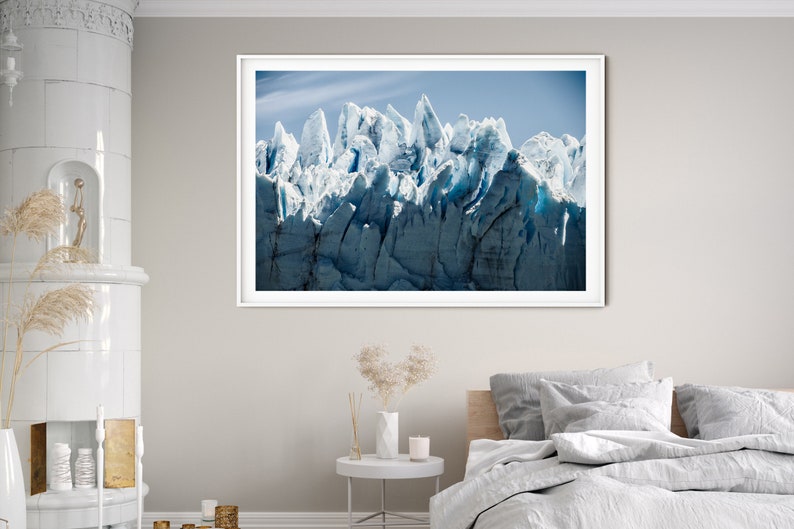 May include: A framed photograph of a glacier with a blue and white color scheme. The glacier is a large mass of ice and snow that has been sculpted by the wind and weather. The photograph is taken from a low angle, giving the viewer a sense of the glacier's immense size.