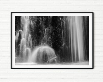 May include: A black and white photograph of a waterfall cascading over rocks. The water is blurred, creating a sense of motion. The background is dark and out of focus.