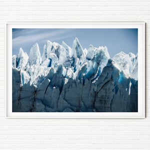 May include: A close-up view of a glacier with sharp, jagged edges. The ice is a bright blue and white color, and the sky is a clear blue.