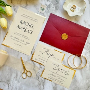May include: Wedding invitation suite with gold accents and a burgundy envelope. The invitation features the names Rachel and Marcus, the date Sunday, June 3rd, 2025, and the location Los Angeles Hilton Hotel, 130 W. Paces Ferry Rd, Atlanta, GA. The RSVP card includes a gold accent and the text "Kindly RSVP by April 3rd". The details card features a gold accent and the text "Details", "The following hotel has rooms reserved", "Marble Wedding", "The Westin Buckhead Atlanta", "338 Peachtree Rd NE, Atlanta, GA 30325".