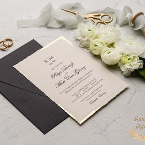 May include: A cream-colored wedding invitation with gold accents and a torn edge. The invitation features the couple's names, "Raya Denizli and Mert Can G&uuml;ney", and the date of their wedding, "May 22, 2023". The invitation also includes the location of the wedding, "Lords Palace Hotel", and the time of the ceremony, "6:30 PM".