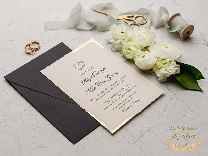 May include: A cream-colored wedding invitation with gold accents and a torn edge. The invitation features the couple's names, "Raya Denizli and Mert Can G&uuml;ney", and the date of their wedding, "May 22, 2023". The invitation also includes the location of the wedding, "Lords Palace Hotel", and the time of the ceremony, "6:30 PM".