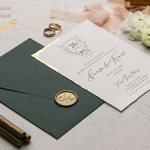 May include: A white wedding invitation with gold accents and a decorative border. The invitation features the text "Cansu & Kemal" and the date "26 August 2023".