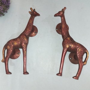 Puede incluir: Un par de tiradores de puerta de latón antiguo con forma de jirafas con un acabado marrón rojizo y manchas doradas.