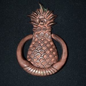 May include: A brown and gold pineapple-shaped door knocker with a ring handle.