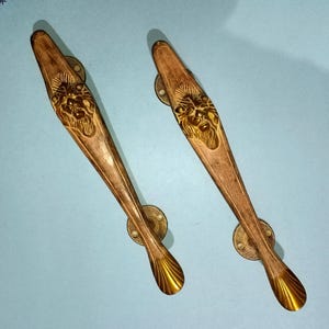 Puede incluir: Dos tiradores decorativos para puertas con diseño de cabeza de león. Los tiradores son de madera con acabado de latón. Los tiradores miden aproximadamente 30 cm de largo.