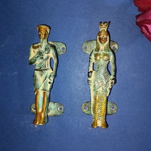 May include: A pair of decorative door handles with a green and gold finish. The handles feature a stylized design of a man and a woman in traditional clothing.