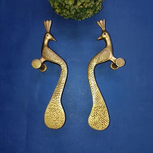May include: A pair of gold peacock door handles with intricate details. The handles are made of solid brass and feature a peacock design with a raised tail and head.