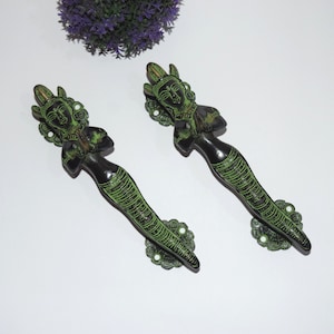 Puede incluir: Dos tiradores de puerta de latón antiguo con pátina verde. Cada tirador presenta un diseño detallado de una mujer en una pose tradicional india.