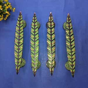 May include: Four leaf-shaped door handles in a row. Each handle is green with a black and gold chevron pattern. The handles are mounted on circular green backplates. The background is a solid blue.