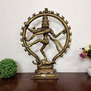 May include: A bronze statue of a dancing deity, framed by a circular halo with flame-like accents. The figure is posed dynamically, with multiple arms and intricate details. The statue is on a square base.