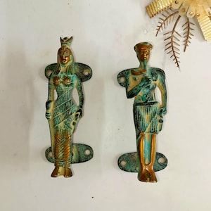 May include: A pair of antique bronze door handles, one showing a crowned woman and the other a man. The handles have a weathered, turquoise and gold finish, and are mounted on oval backplates.