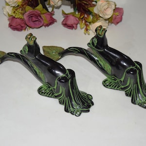 May include: A pair of black and green decorative door handles shaped like stylized mythical creatures. The handles have a detailed design with green accents.