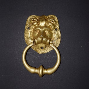 May include: A gold lion's head door knocker with a ring handle.