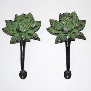 Puede incluir: Un par de tiradores de puerta decorativos con un diseño de flor de loto. Los tiradores están hechos de latón y tienen un acabado de pátina verde. Los tallos de los tiradores son negros.