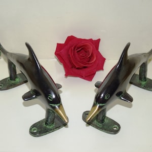 Op de afbeelding: Een paar zwarte en groene dolfijn deurgrepen. De grepen zijn gemaakt van metaal en hebben een gepolijste afwerking.